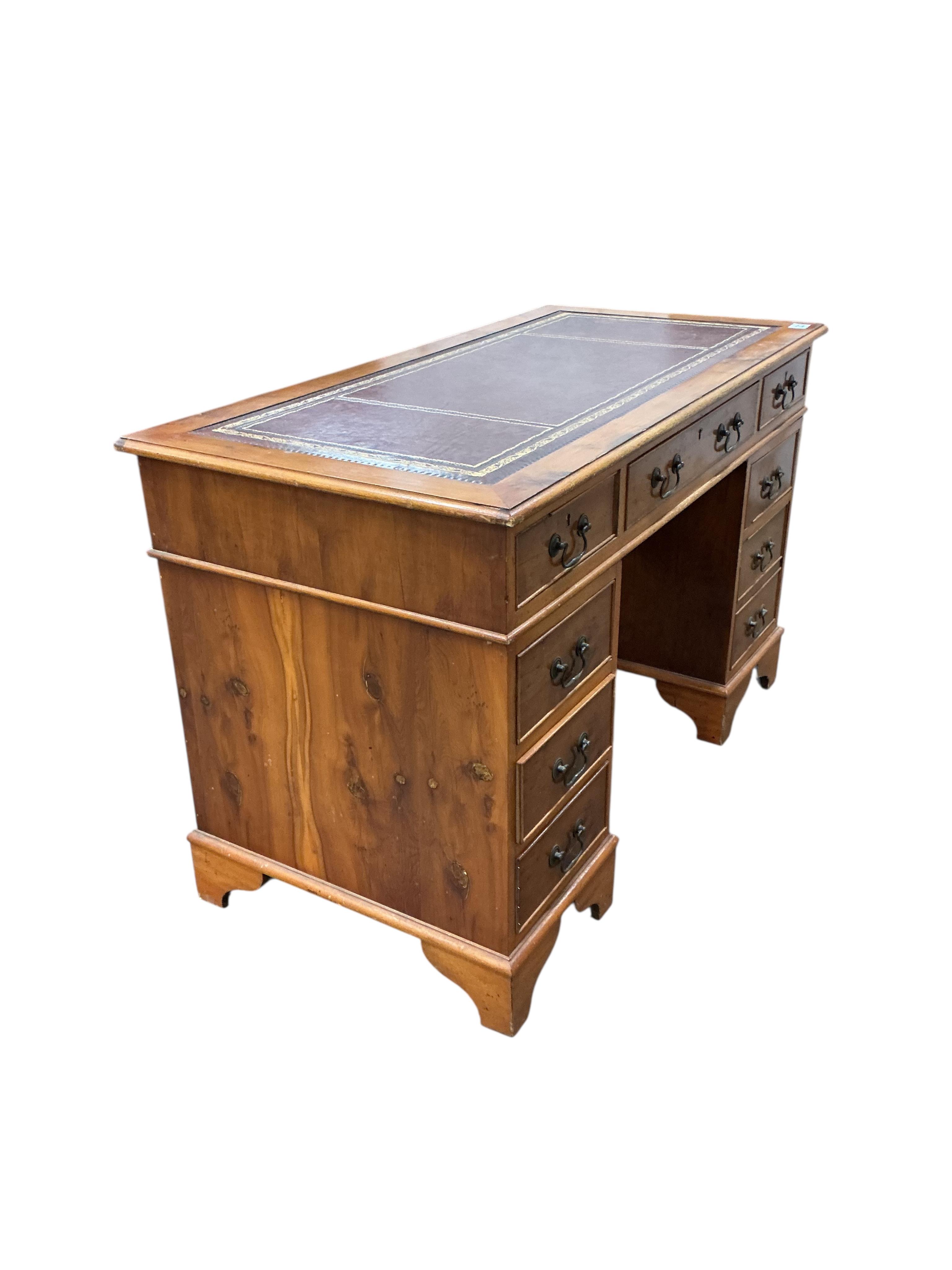 A reproduction yew pedestal desk, width 132cm, depth 61cm, height 77cm and a buttoned burgundy leather swivel desk chair